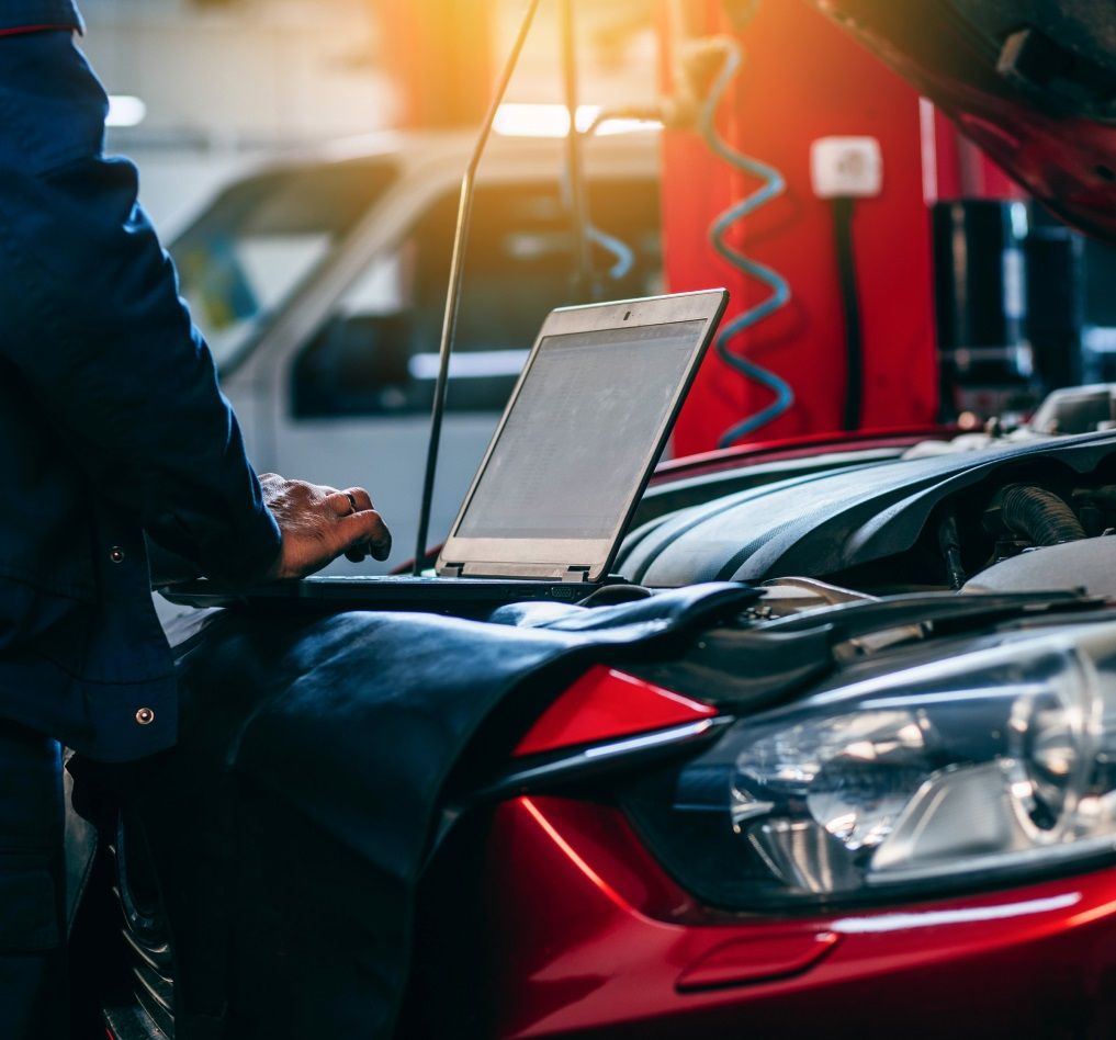 Mechaniker diagnostiziert Motor mit Laptop.